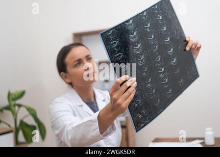 Diagnosi ortopedica: Il medico utilizza un computer portatile per valutare le pellicole radiologiche e le scansioni RM su un tavolo. Foto Stock
