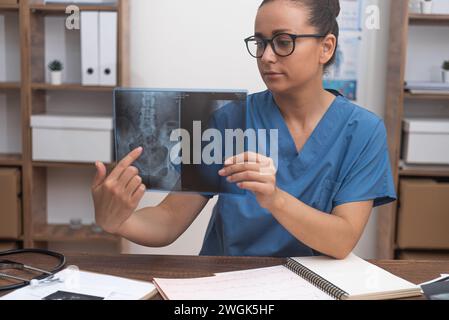 medico donna che punta la pellicola radiografica che mostra alla telecamera durante la consultazione online di telemedicina Foto Stock