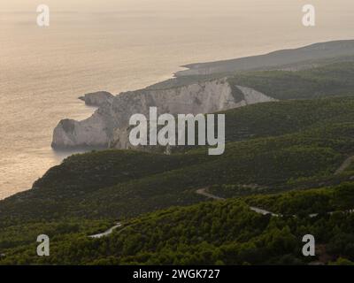 Alberi verdi al tramonto e vista sul mare su un'isola greca. Tramonto mediterraneo dal punto panoramico di Agalas. Campi verdi e foreste a Zante, Grecia. Foto Stock