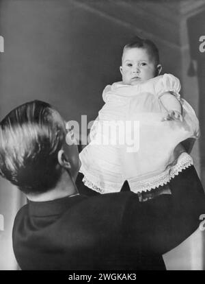 Una fotografia che cattura un momento mentre il principe Filippo tiene in aria suo figlio neonato, Carlo III. Scattata poco dopo la nascita di Carlo il 14 novembre 1948, questa immagine riflette la loro prima relazione. Come primogenito del principe Filippo e della regina Elisabetta II, Carlo nacque in un ruolo di primo piano all'interno della monarchia britannica. I futuri ruoli di Carlo come Principe di Galles e infine Re nel 2022 sono ancora anni avanti, rendendo questa immagine un'istantanea di un momento più semplice nella vita del giovane principe. Foto Stock