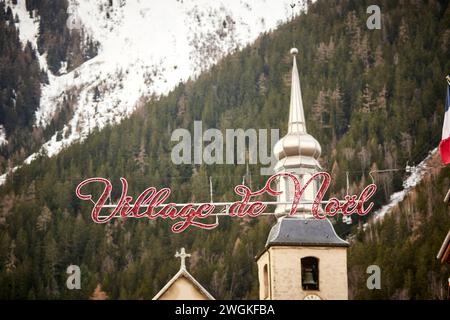 Chamonix Mont Blanc, Francia. Village de Neol chalet in legno, area del mercato di Natale incorniciata dalla chiesa di San Bernardo del Monte bianco di Paroisse Foto Stock