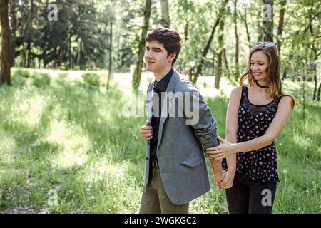 Il ragazzo guida la ragazza per mano. Una coppia in amore cammina in un parco di primavera tenendo Hands.Lifestyle di persone di felicità. Foto Stock