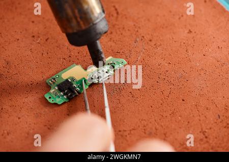vista ridotta di tecnici specializzati che riparano microschemi elettronici in officina, piccole imprese Foto Stock