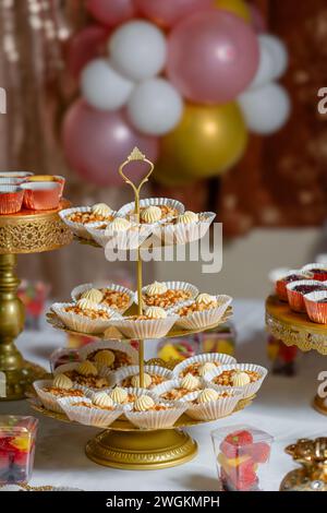 I cupcake di compleanno su un'esposizione a tre livelli sono dotati di palloncini natalizi sullo sfondo Foto Stock