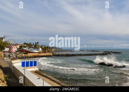 Vista sopraelevata del lungomare con alte onde che si infrangono sulla spiaggia e il Luna Park con la ruota panoramica in inverno, Sanremo, Liguria, Italia Foto Stock