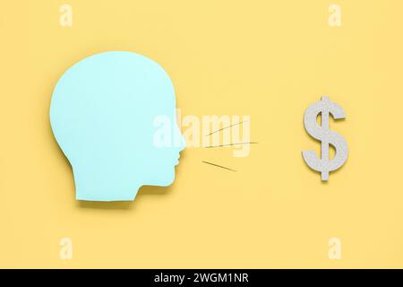 Testa umana in carta con lampadina e simbolo del dollaro su sfondo giallo. Idea di business Foto Stock