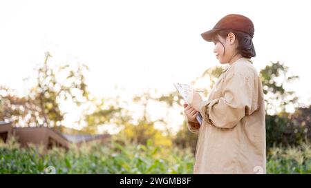 Una giovane donna asiatica proprietaria di un'azienda agricola di fiori o agronomo che lavora in un'azienda agricola di fiori, controllando la qualità del fiore. Foto Stock