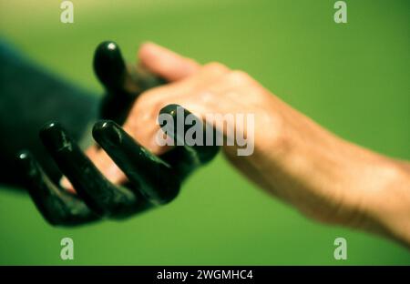 Mano umana che tiene la mano scolpita nera Foto Stock