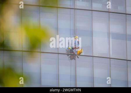 22 gennaio 2024: I lavoratori puliscono il vetro su edifici alti a ho chi Minh City, Vietnam Foto Stock