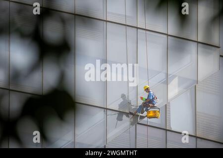 22 gennaio 2024: I lavoratori puliscono il vetro su edifici alti a ho chi Minh City, Vietnam Foto Stock