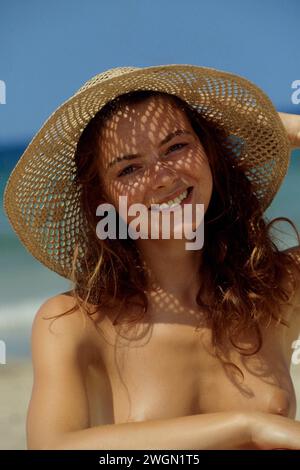 grazioso ritratto di una giovane donna dai capelli rossi con capelli di paglia blu che sorride davanti fotocamera blu skyback terra vacanze estive Foto Stock