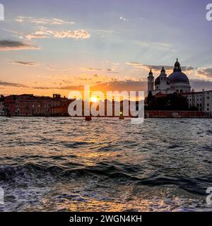Una vista mozzafiato si dispiega mentre il sole scende sotto l'orizzonte, proiettando un bagliore dorato sulla bellezza senza tempo di Venezia, dipingendo il cielo di sfumature Foto Stock