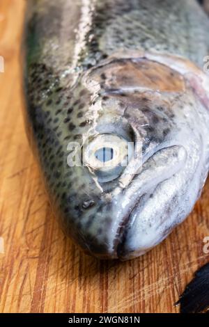 Testa di pesce crudo crudo e crudo su un tavolo di legno da cucina, primo piano verso il basso Foto Stock