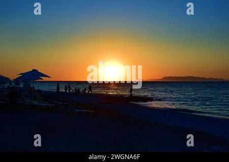 Sagome di persone durante il tramonto sulla spiaggia di Ialyssos nell'isola greca di Rodi Foto Stock