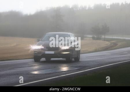 Auto che viaggia lungo l'autostrada in una giornata piovosa e tempestosa con scarsa visibilità e fari luminosi distorti all'interno della telecamera. Foto Stock