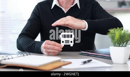 Assicuratore che protegge un bus di carta con la mano Foto Stock