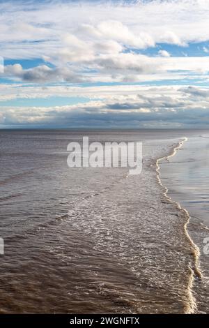 Guardando lungo il bordo dell'acqua dal molo, a Skegness nel Lincolnshire Foto Stock