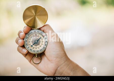 Primo piano della mano di una donna che tiene in mano una bussola durante un'escursione nella foresta. La bussola simboleggia Foto Stock