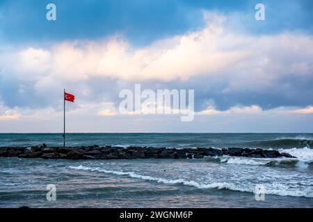 Una bandiera turca sventolava sulla spiaggia vicino all'oceano Foto Stock