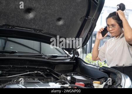 Hai bisogno di aiuto con il guasto dell'auto donna seria ascolta i consigli e la spiegazione del servizio di riparazione auto di emergenza al telefono. Foto Stock