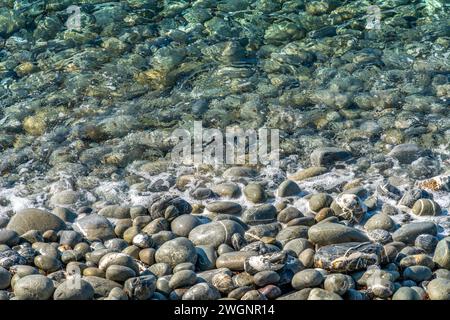 Soleggiato paesaggio sul mare che mostra una riva con molti ciottoli visti in Italia Foto Stock