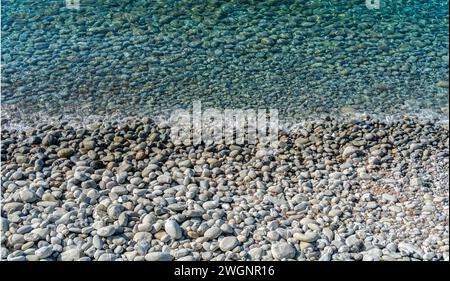 Soleggiato paesaggio sul mare che mostra una riva con molti ciottoli visti in Italia Foto Stock