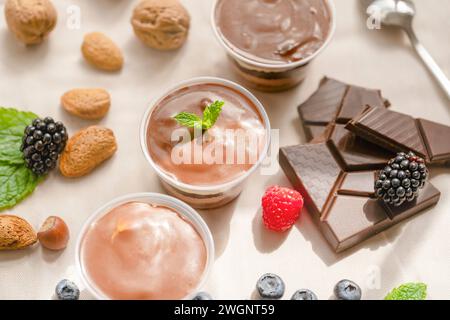 Tre chicchi di cioccolato in tazze con pezzi di cioccolato, fragole, nocciole Foto Stock