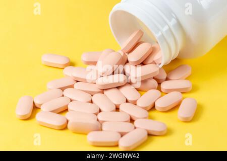 Pillole vitaminiche che fuoriescono da un flacone di plastica Foto Stock