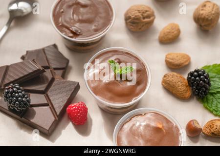 Tre chicchi di cioccolato in tazze con pezzi di cioccolato, fragole, nocciole Foto Stock