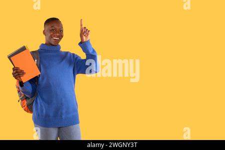 donna con un maglione blu che tiene i notebook con lo zaino che solleva l'indice come idea su sfondo giallo, viaggiando. Fatevi un'idea. Viaggio, educ Foto Stock