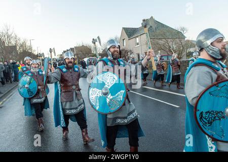 Membri della Jarl Squad del 2024 che marciano attraverso Lerwick sulle isole Shetland durante l'Up Helly AA festival. Le ragazze del primo anno erano nella Jarl Squad. Foto Stock