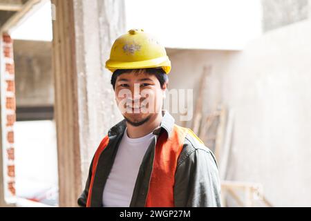 Giovane muratore sorridente che indossa un elmetto Foto Stock