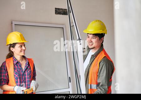 Carpentieri sorridenti che installano il telaio della finestra Foto Stock