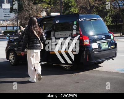 TOKYO, GIAPPONE - 14 gennaio 2024: Una persona che sale su un taxi su un'ampia strada nell'area di Takebashi a Tokyo. Foto Stock