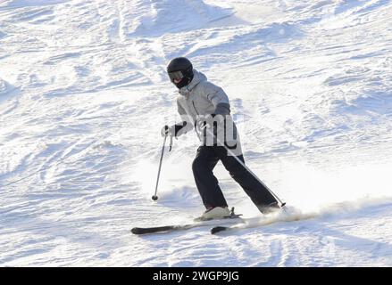Uno sciatore adulto che si diverte a trascorrere una giornata sulla pista la vigilia di Capodanno 2023. Foto Stock