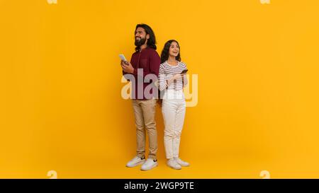 Eccitato giovane indiano uomo e donna con i telefoni in mano Foto Stock