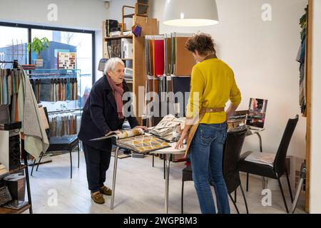 Tappezzeria femminile che aiuta il cliente a scegliere il tessuto Foto Stock