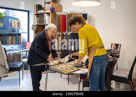 Tappezzeria femminile che aiuta il cliente a scegliere il tessuto Foto Stock