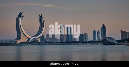 Skyline di Lusail nella città di Lusail, in Qatar, incluso il progetto delle Torri Katara dal porto turistico di Lusail per le riprese al tramonto. Concetto di industria delle costruzioni. Foto Stock