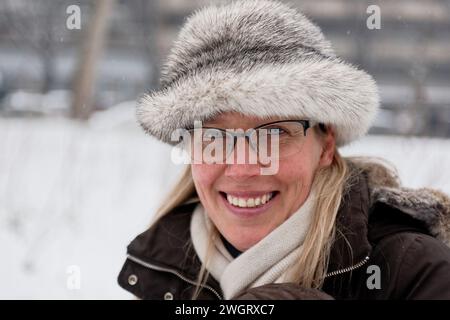 Donna bionda vestita per l'inverno con cappello e sciarpa in pelliccia, Milano, Italia Foto Stock