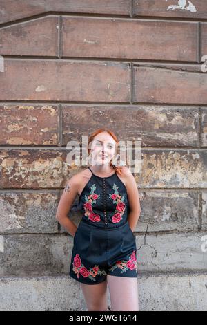 Una donna con i capelli rossi di fronte a un vecchio muro, Roma, Italia Foto Stock