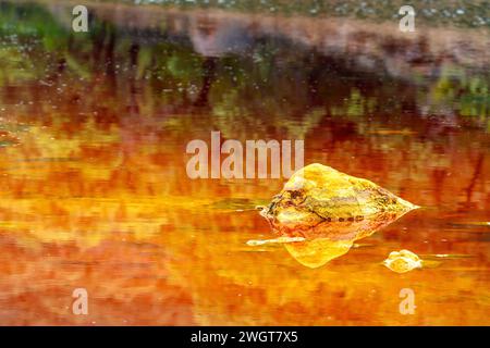 Impressionanti strati di terra e una vivace striscia di acqua rossa fiancheggiano il terreno incrinato del Rio Tinto Foto Stock