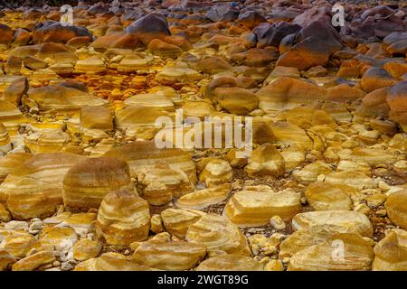 I caldi depositi minerali arancioni del Rio Tinto scolpiscono un paesaggio strutturato con pozzanghere riflettenti Foto Stock