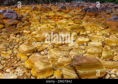 I caldi depositi minerali arancioni del Rio Tinto scolpiscono un paesaggio strutturato con pozzanghere riflettenti Foto Stock