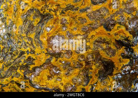 I caldi depositi minerali arancioni del Rio Tinto scolpiscono un paesaggio strutturato con pozzanghere riflettenti Foto Stock