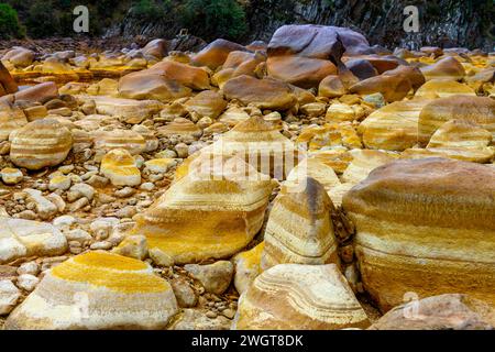 I caldi depositi minerali arancioni del Rio Tinto scolpiscono un paesaggio strutturato con pozzanghere riflettenti Foto Stock