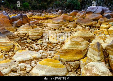 I caldi depositi minerali arancioni del Rio Tinto scolpiscono un paesaggio strutturato con pozzanghere riflettenti Foto Stock