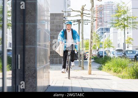 Giovane in bicicletta in città con il casco Foto Stock