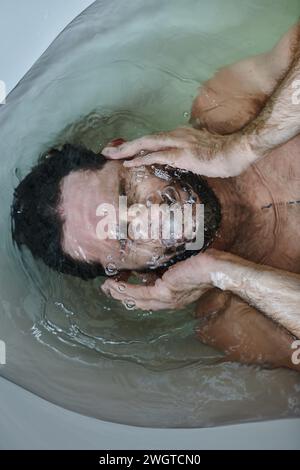 uomo frustrato e depresso con barba annegante nella vasca da bagno durante il crollo, consapevolezza della salute mentale Foto Stock