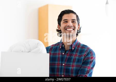 giovane uomo che porta una scatola con trapunta Foto Stock